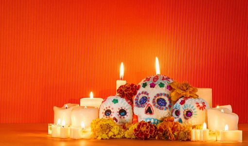 Colorful sugar skulls and marigolds on a candlelit altar for Dia de los Muertos.